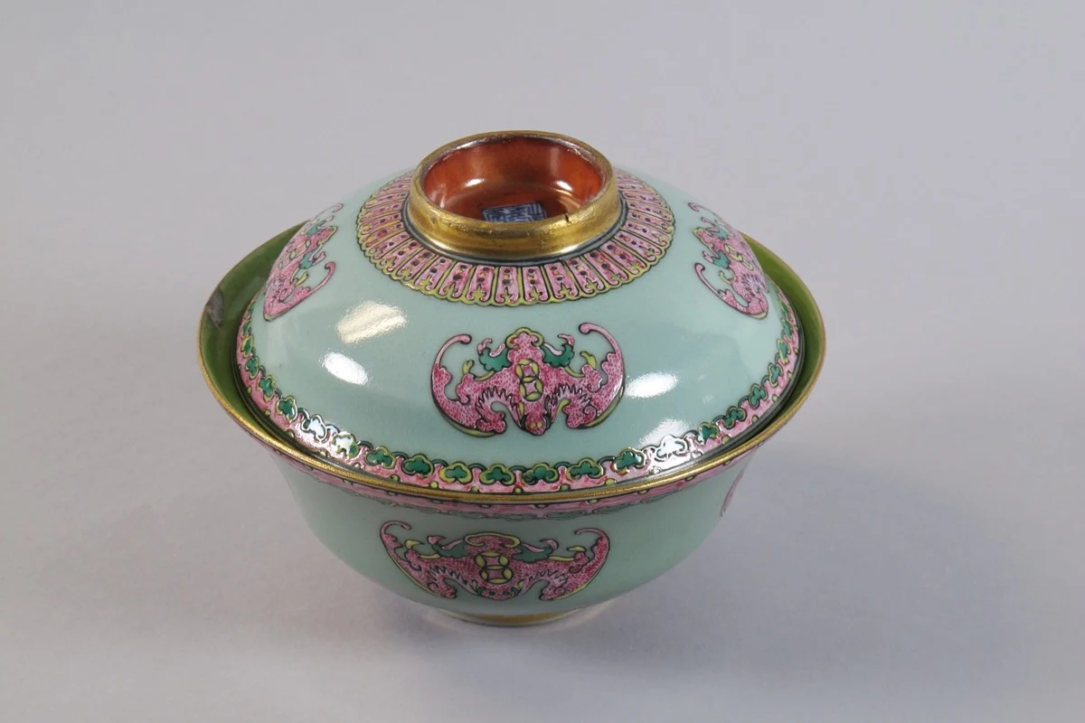 A Qing porcelain covered bowl painted with repeated pink bat motifs on pale green enamel