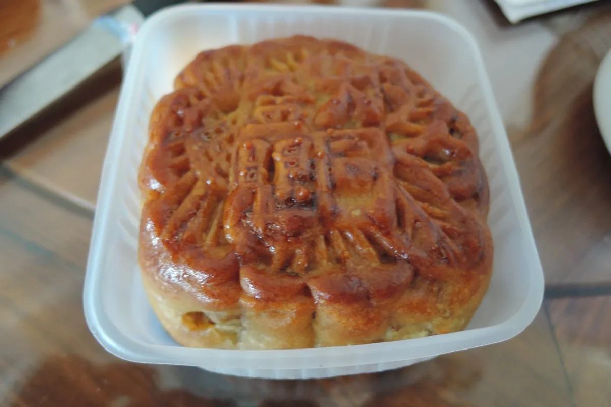A round mooncake with a stamped top served in a small tray